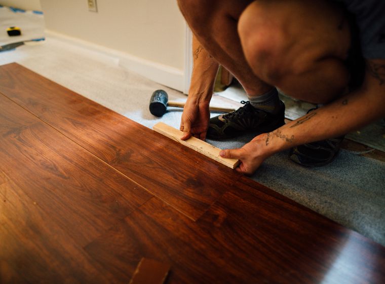 Installer laying laminate wood flooring with a mallet