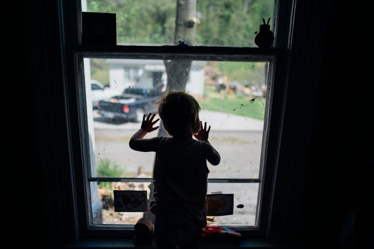 Silhouette Of Little Boy Looking Out Window