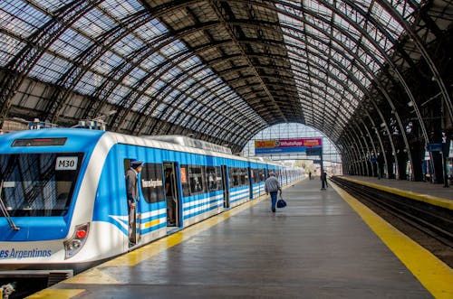 Faceless passengers and train driver at modern train station under arched roof