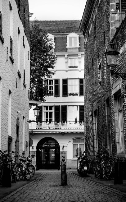 Black and white exterior of aged street of city with shabby facades of buildings and bicycles