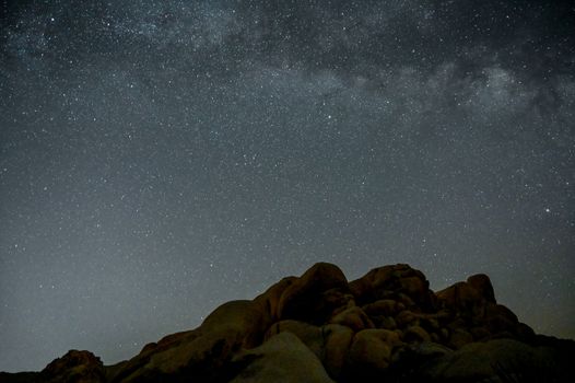 加州的沙漠岩石地层上方，夜空布满了星星，令人惊叹
