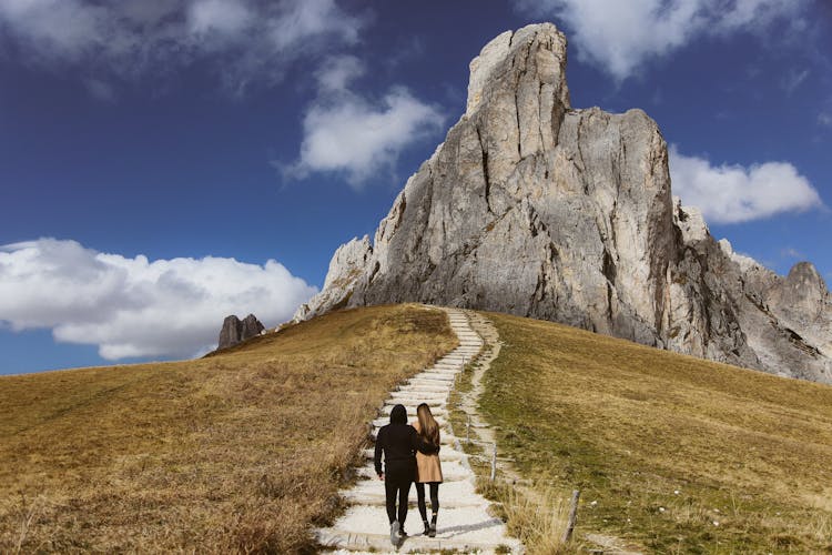 A Couple Walking On A Cobblestone Path Towards Ra Gusela