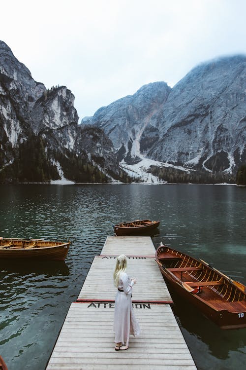 A Woman Standing on a Wooden Dock near the Boats