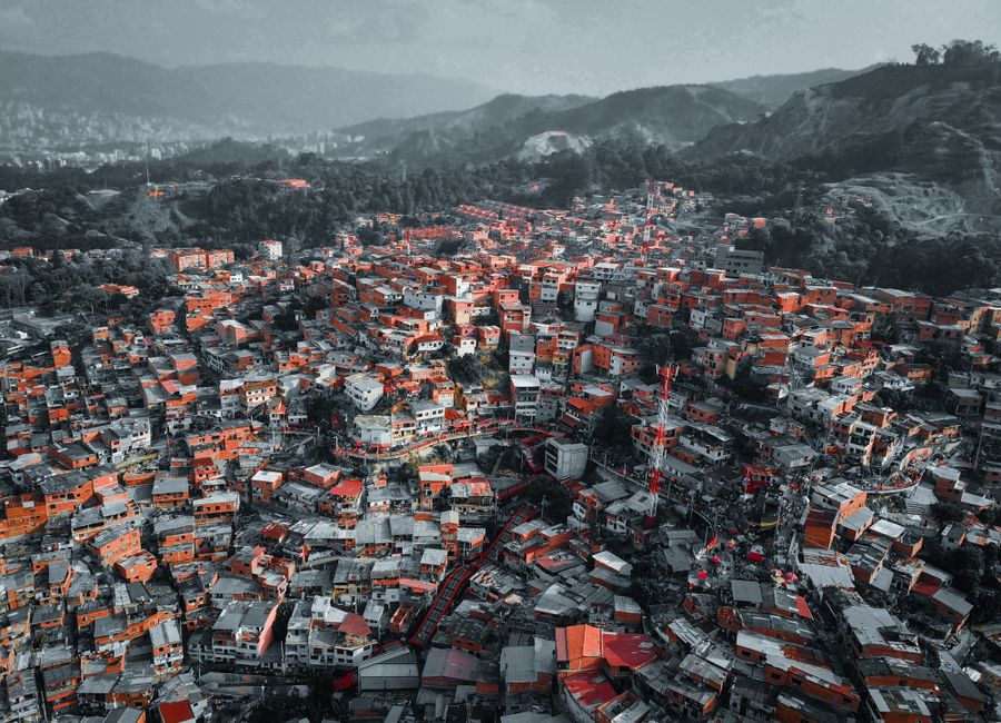 Colorful urban landscape of Medellín viewed from above, showcasing dense housing and surrounding hills.