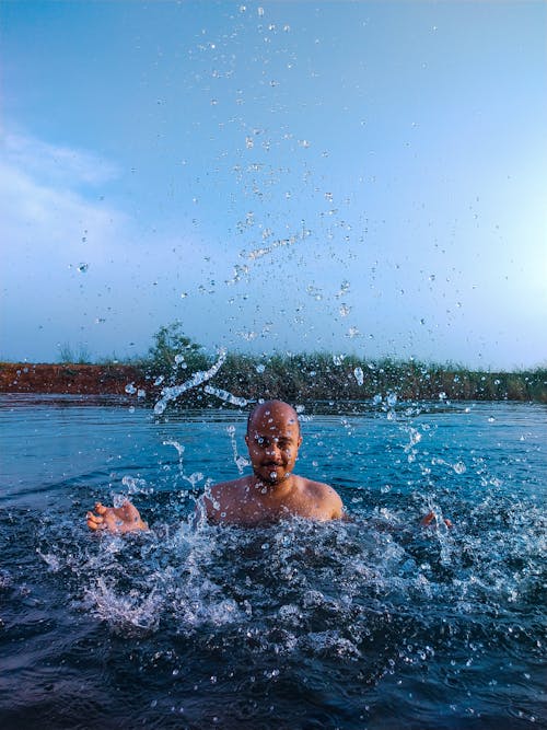 Free Man splashing water in lake in countryside Stock Photo