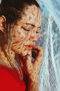 一位身着红衣的平和女子，脸上映着蕾丝般的阴影，她闭着双眼，营造出梦幻而宁静的氛围