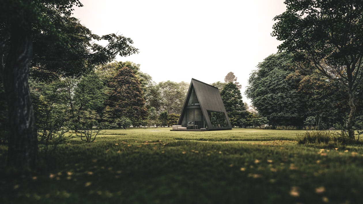 Free Exterior of rural creative cottage in shape of triangle located on grassy lawn in abundant forest Stock Photo