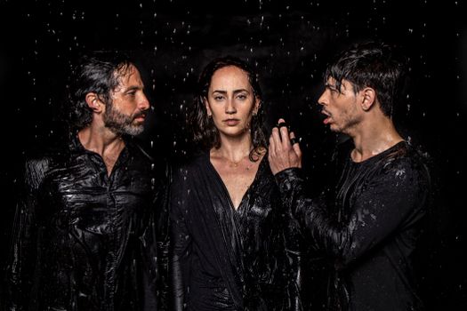 Photogenic talented artists wearing wet black clothes standing in studio under water drops
