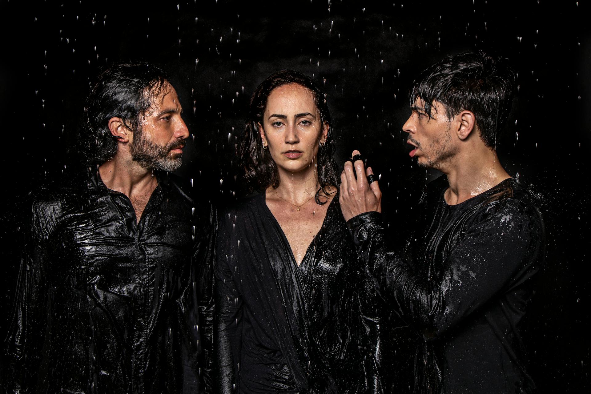 Photogenic talented artists wearing wet black clothes standing in studio under water drops