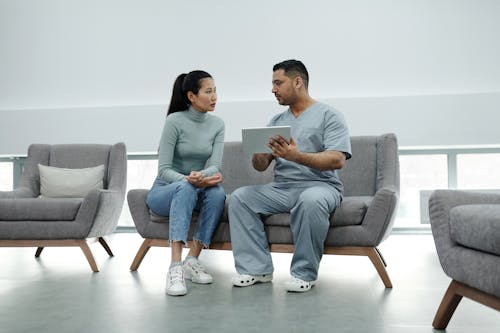 Free A Doctor Talking to a Patient while Holding a Tablet Stock Photo