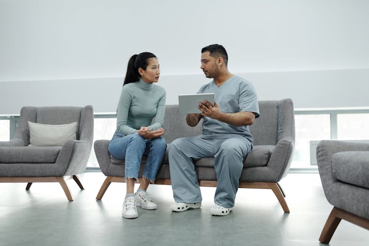 A Doctor Talking To A Patient While Holding A Tablet