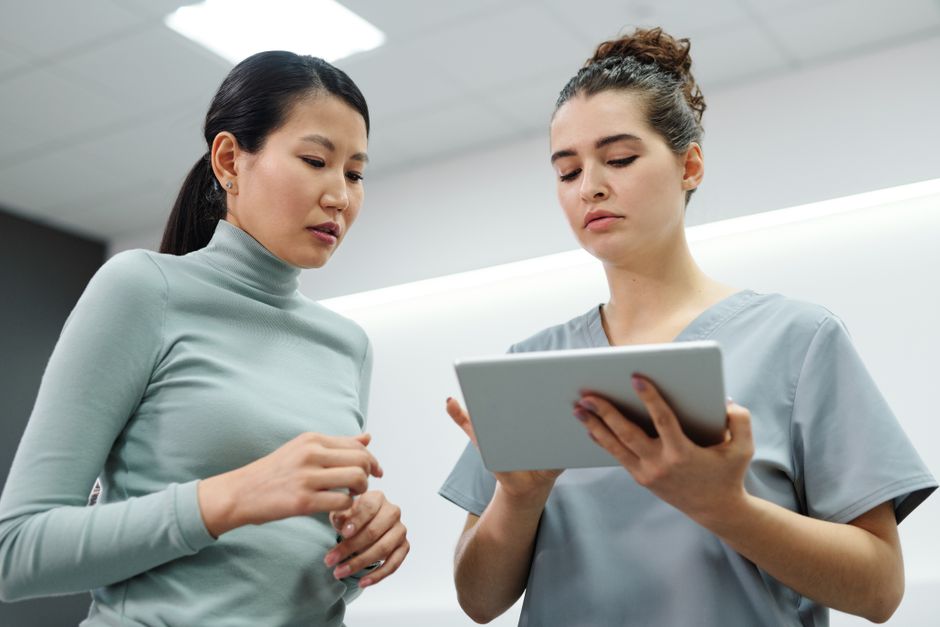Doctor and patient reviewing medical results on a tablet — medical screening including EKG is required before any psychedelic plant medicine ceremony