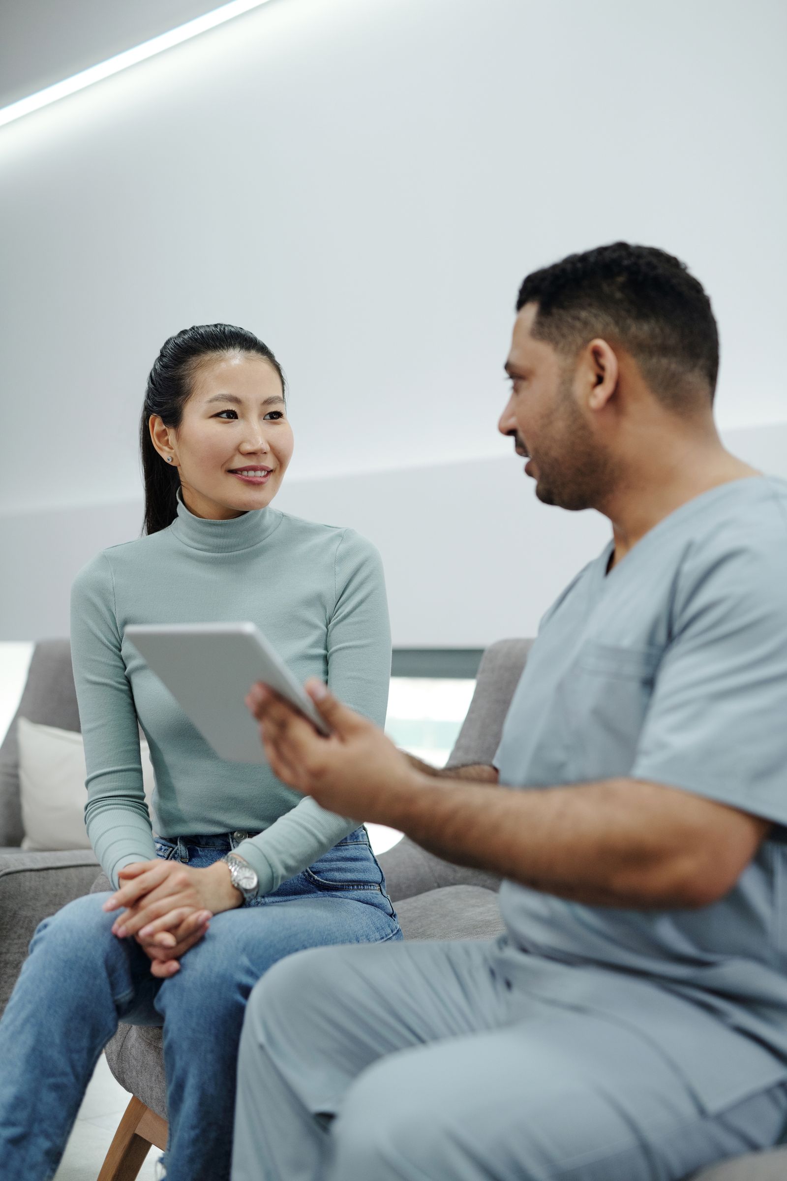 A woman sitting and speaking with a healthcare provider in scrubs during a consultation