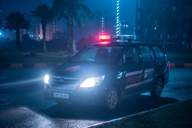 A Police Car Parked By The Roadside At Night