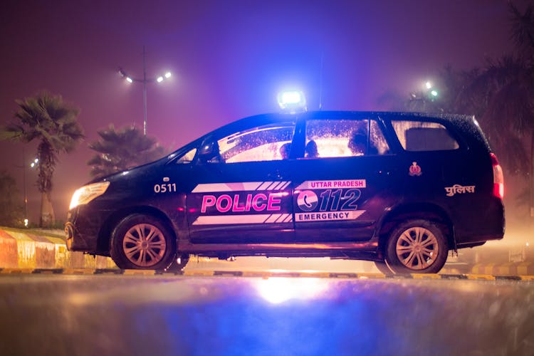 Side View Of A Police Car Parked By The Roadside At Night