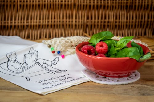 A Bowl of Raspberries and Basil Leaves