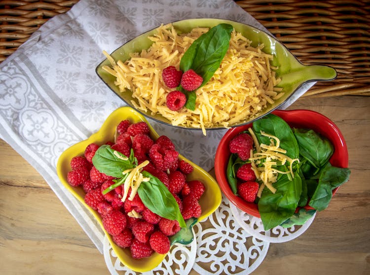 Overhead Shot Of Raspberries, Basil Leaves And Grated Cheese