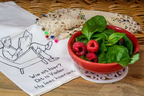 A Bowl of Raspberries and Basil Leaves