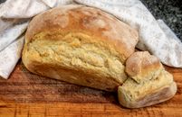 Delicious homemade bread loaf with a crispy crust on a wooden board, perfect for culinary displays.