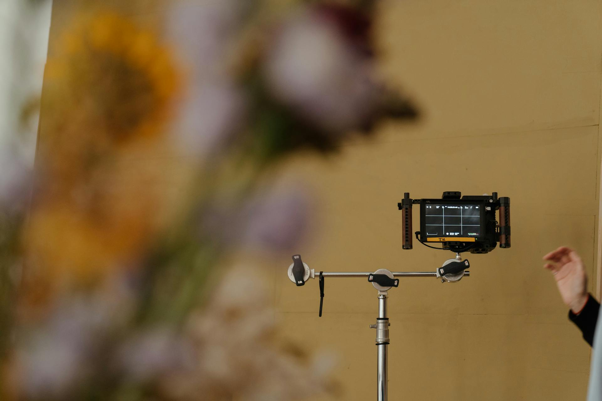 A professional camera setup with floral foreground adds artistic flair to the image.