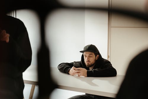 Free Man in Black Hoodie and Black Cap Sitting on Chair Stock Photo