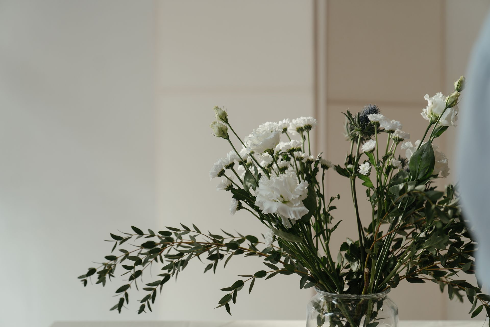 A tranquil arrangement of white flowers in a glass vase with soft, natural lighting.