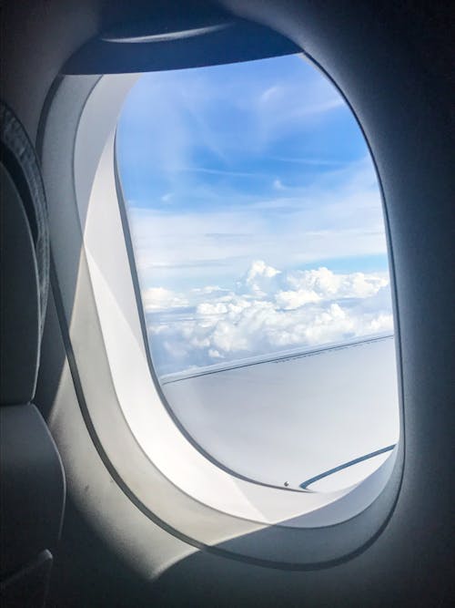 Free View from airplane window on fluffy white clouds floating on blue sky on sunny day Stock Photo