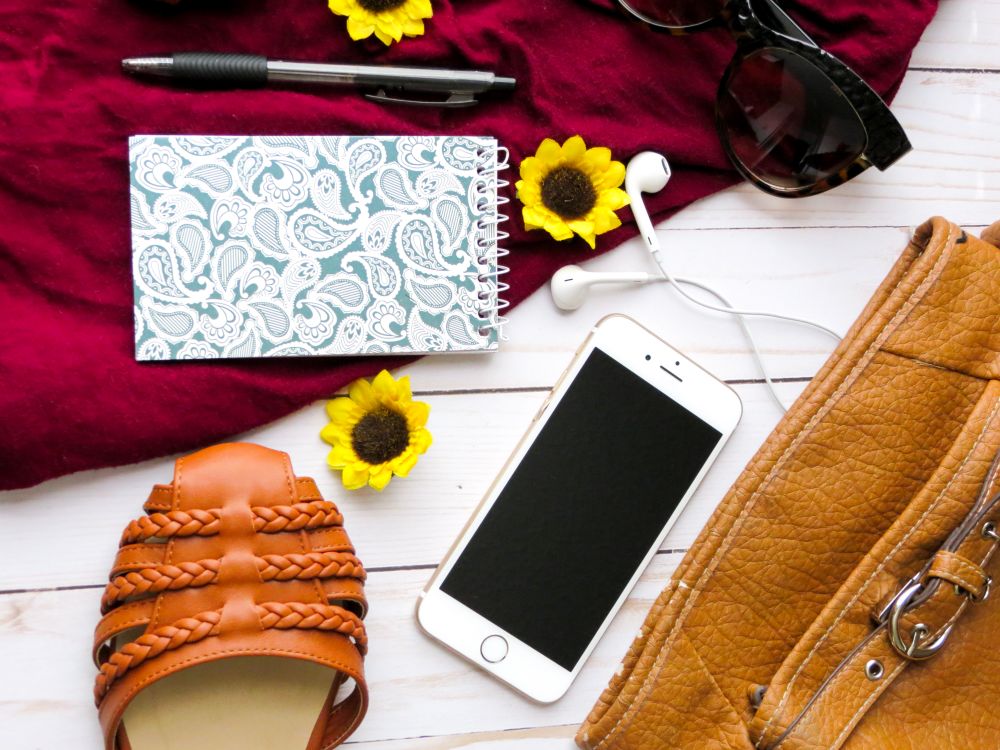 Flat lay de acessórios: bolsa e detalhes em tons dourados