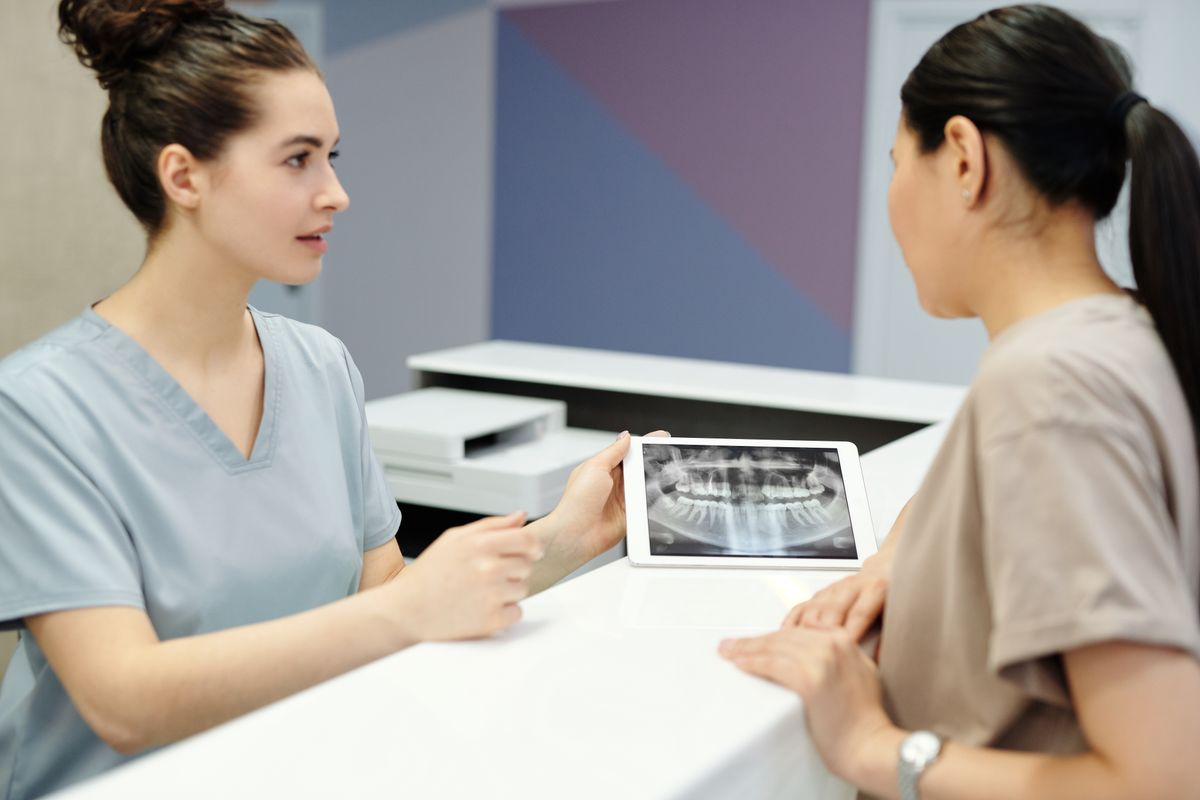 Dentist assessing a dental X-ray with a patient to plan bone grafting