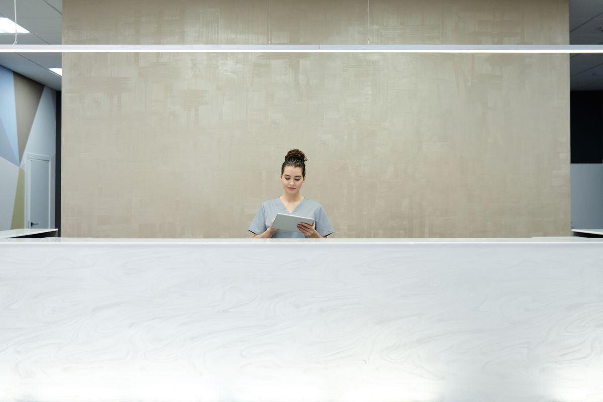 Receptionist using a tablet behind a clean, uncluttered reception counter in a modern office