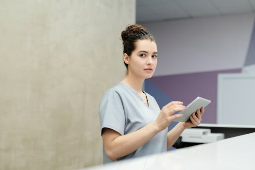 Professional receptionist using a tablet device at a modern office reception desk.