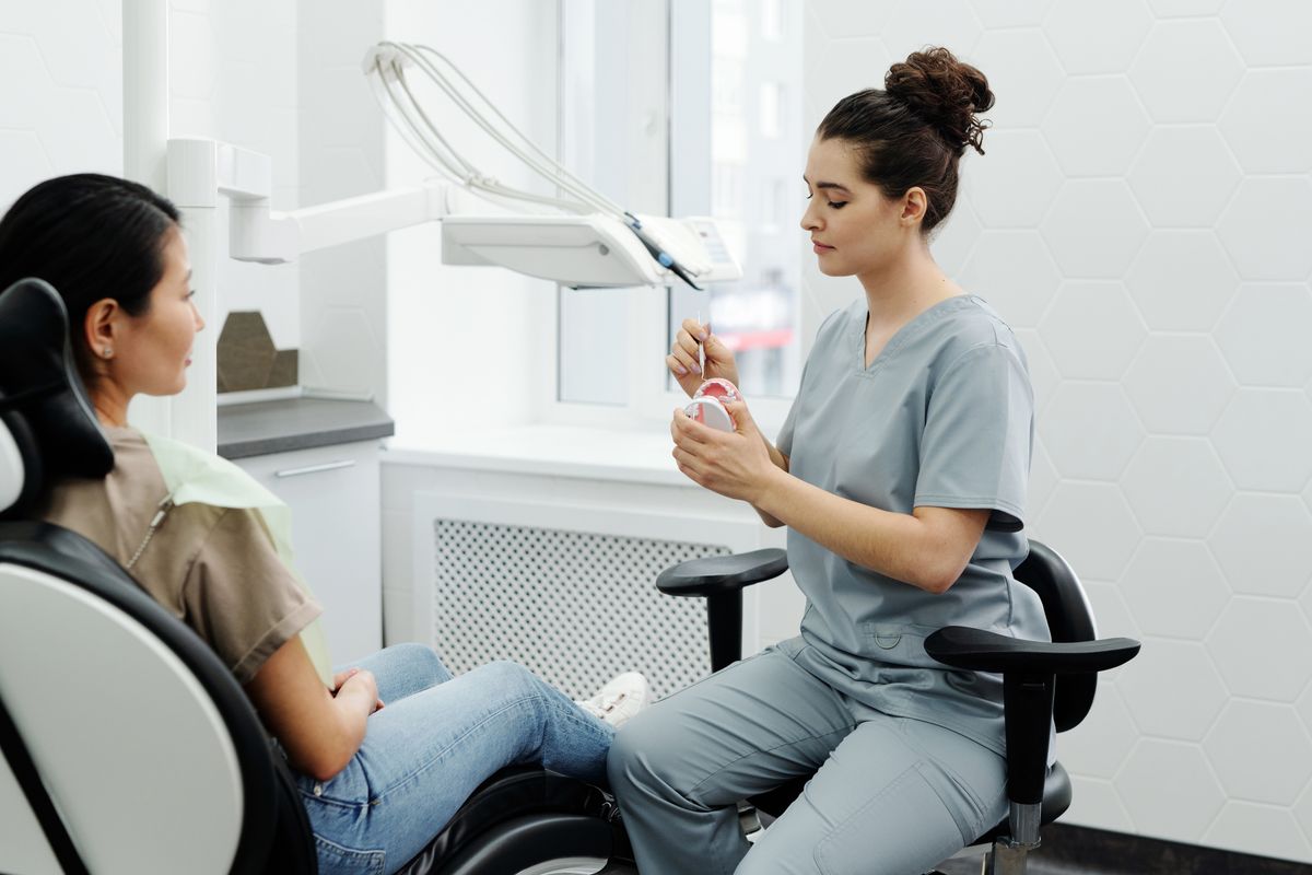 Female dentist explaining a dental implant model to a woman in her clinic