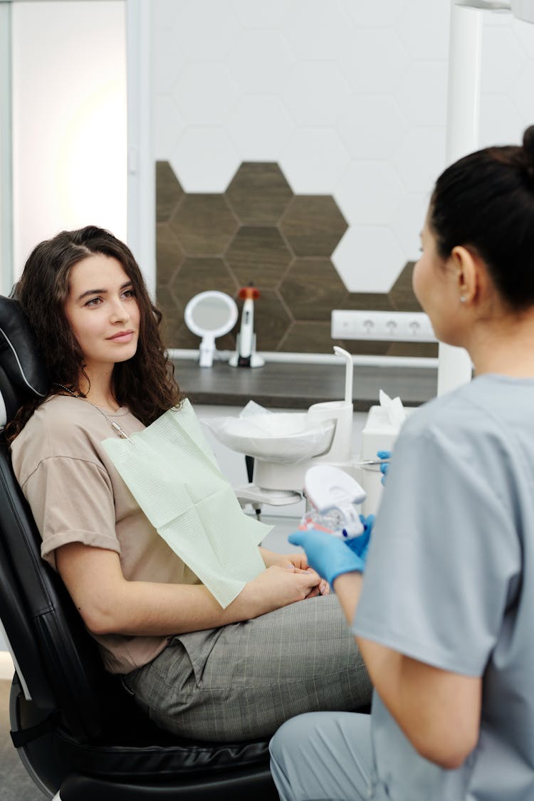 Woman In Brown Shirt Sitting On Black Dentist Chair