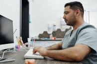 牙医穿着手术服，在牙科诊所的电脑前专注于患者管理工作