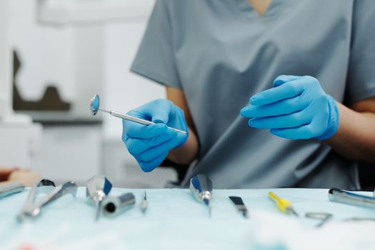 Dentist's gloved hands holding dental tools during a procedure. Focus on hygiene and precision.