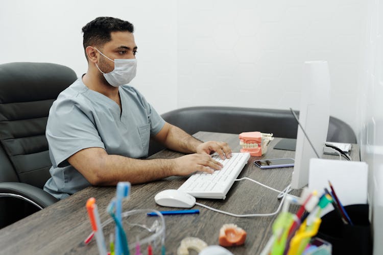 A Man Wearing A Face Mask Using Computer