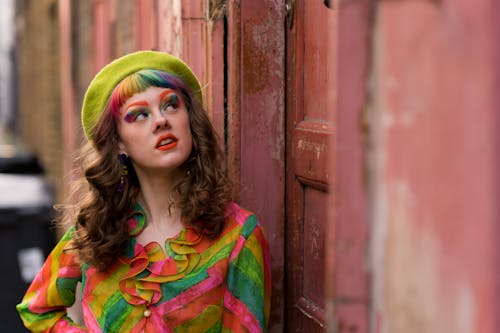 Free Informal young woman in colorful outfit standing near weathered building Stock Photo
