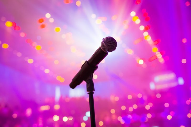 Microphone lit by pink and purple party lights at a karaoke night setup