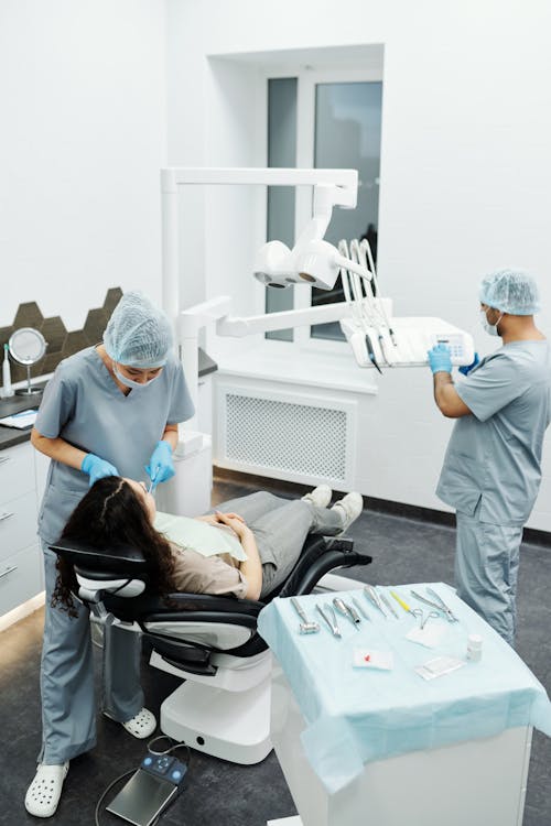 Free People in Scrub Suit Standing Beside a Woman Lying on the Dental Chair Stock Photo