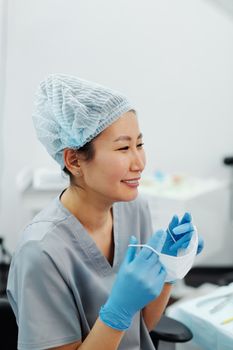一位穿着手术服和个人防护装备的亚洲女医生在医疗诊所休息时微笑着