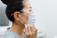 亚洲女医护人员在室内调整防护口罩和护目镜