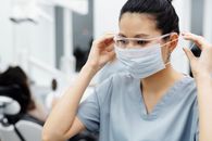 在诊所里，牙科护士穿着手术服，正在调整护目镜和面罩