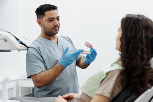 Free Dentist showing a dental model to a patient in a clinical setting. Stock Photo