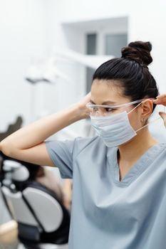 在牙科诊所，亚洲妇女调整了防护眼镜和口罩