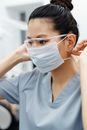 一位亚洲女性医疗保健专业人士在室内调整口罩和护目镜