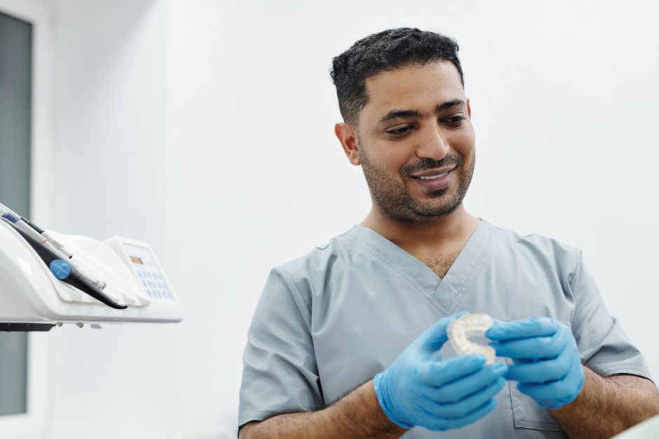 Dental clinician carefully examining a custom acrylic tray before border molding Dental clinician carefully examining a custom acrylic tray before border molding