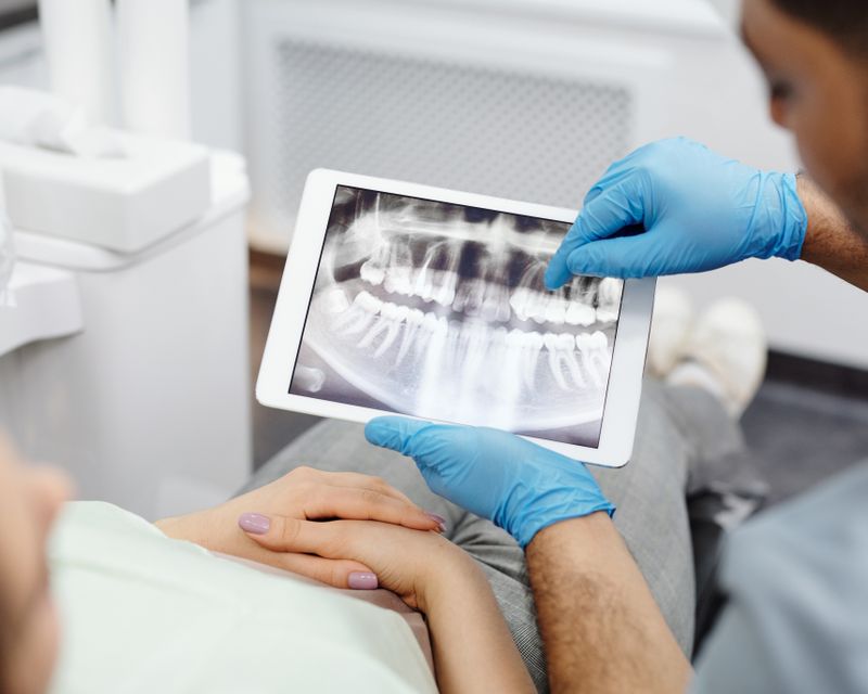 A dentist showing a patient a digital scan of their teeth on a screen