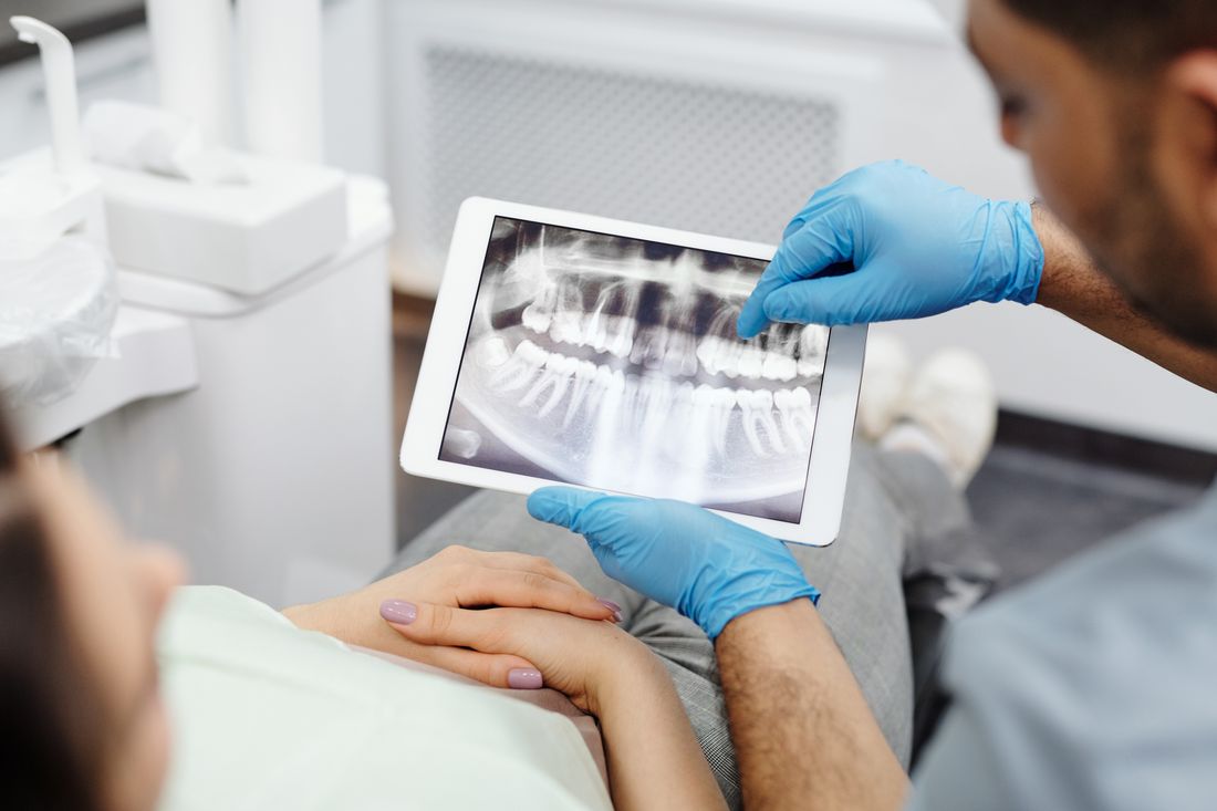 Dentista revisando información digital con una paciente