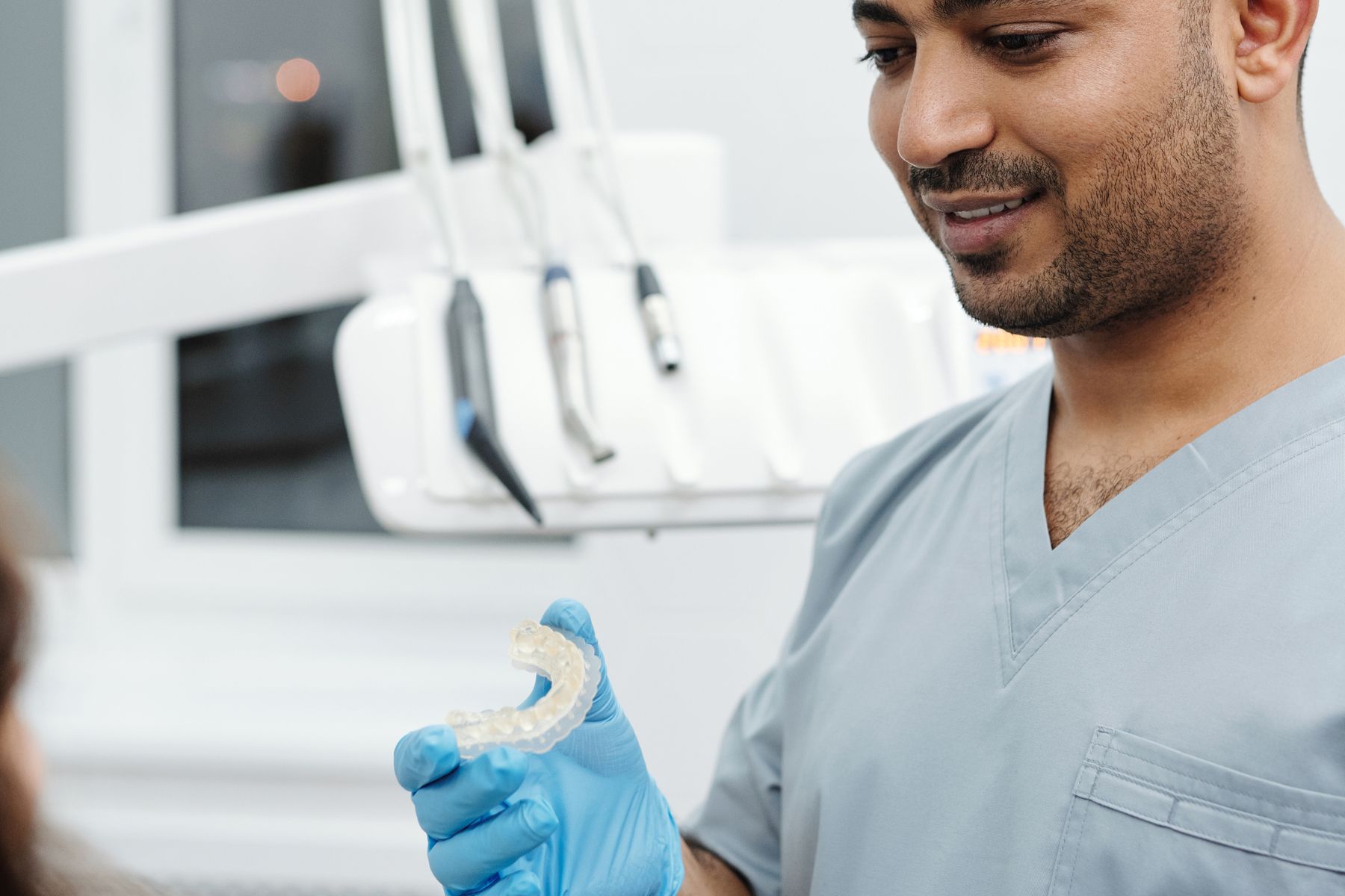 Dental professional showing an aligner to a patient during an orthodontic consultation
