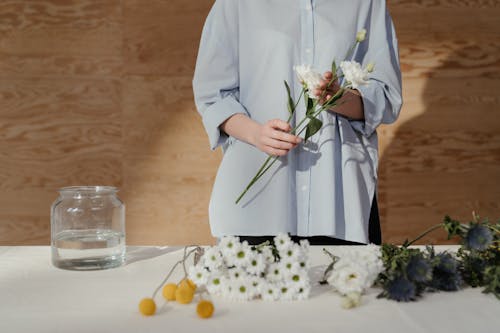 Woman in White Long Sleeve Dress Holding White Flowers